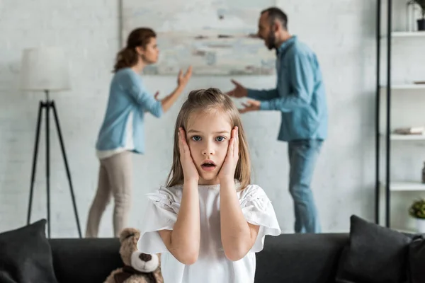 Selective Focus Shocked Kid Touching Face While Standing Quarreling Parents — Stock Photo, Image