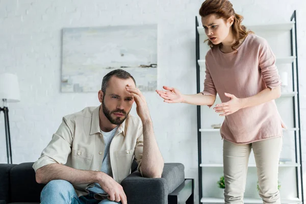 Attraktive Frau Gestikuliert Während Sie Ihren Verärgerten Mann Hause Ansieht — Stockfoto