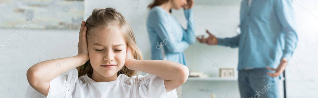 panoramic shot of kid with closed eyes covering ears near parents at home 