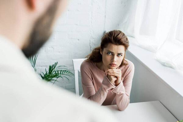 selective focus of upset woman with clenched hands looking at man 