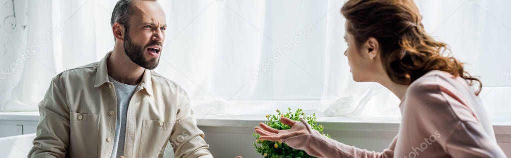 panoramic shot of angry man screaming and looking at woman 