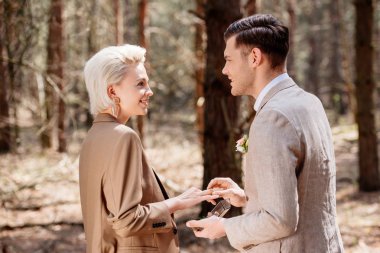 Side view of smiling man proposing to woman in forest clipart