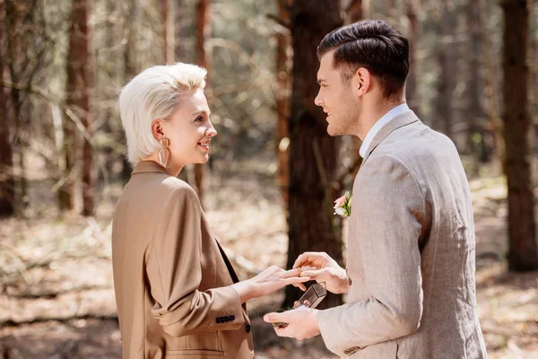 森の中の女性にプロポーズする笑顔の男の側面図 — ストック写真