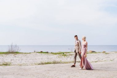 el ele tutuşan ve sahilde yürüyen sadece evli çift tam uzunlukta görünümü
