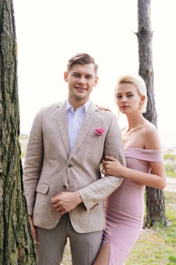 just married couple standing in forest and looking at camera clipart