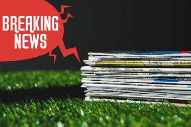 siyah izole son dakika haber yazı ile kırmızı konuşma balonu yakın taze yeşil çim üzerinde farklı baskı gazete yığını