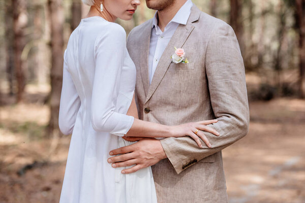 cropped view of just married couple embracing in forest
