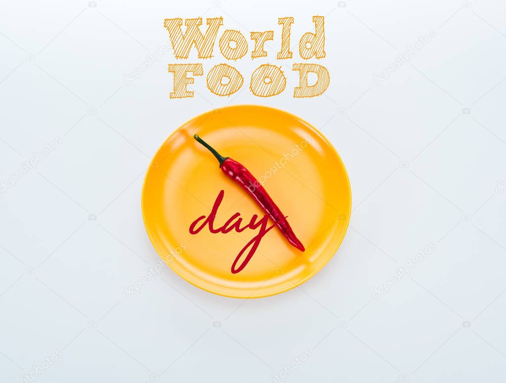 top view of red chili pepper on bright yellow plate with world food day lettering on white background