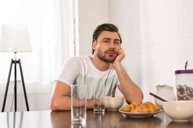 mutfakta kahvaltı sırasında masada oturan ve el ile yüz propping pensive adam