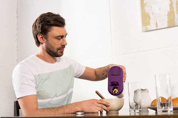 handsome bearded man having breakfast in morning in kitchen