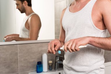 banyoda sabah diş fırçası üzerinde diş macunu uygulayan adam kırpılmış görünümü