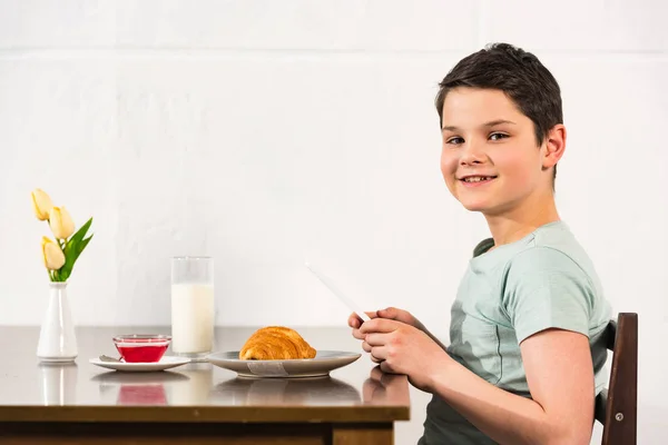 Menino Sorrindo Usando Tablet Digital Durante Café Manhã Cozinha — Fotografia de Stock