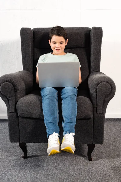 Menino Sorridente Jeans Sentado Poltrona Usando Laptop — Fotografia de Stock
