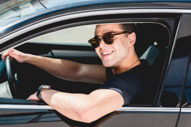 güneş gözlüğü yakışıklı şık adam gülümseyerek ve arabada oturan 