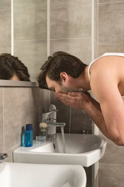 Man Wassen Gezicht Buurt Van Spiegel Ochtend Badkamer — Stockfoto