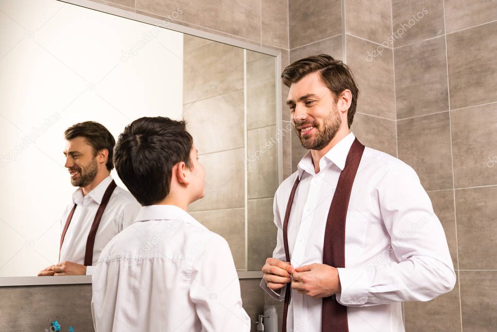 father and son dressing in formal wear in bathroom