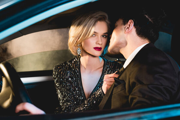 стильный мужчина и красивая модная молодая женщина в официальной одежде, сидящая в машине
