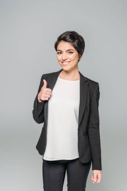 mutlu karışık ırk iş kadını başparmak gösteren ve gri izole kamera gülümseyen