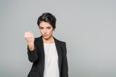 kızgın karışık ırk iş kadını kameraya bakıyor ve gri izole yumruk gösteren 