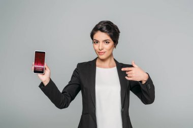 gri izole ekranda ticaret kursları uygulaması ile akıllı telefon gösteren güzel karışık ırk iş kadını