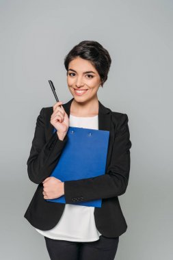 gri izole pano ve kalem tutarken kameraya gülümseyen neşeli karışık Yarış iş kadını