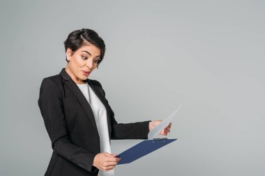 şaşırttı karışık ırk iş kadını pano bakarak ve gri izole gesturing