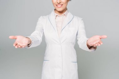 partial view of mixed race doctor showing welcome gesture isolated on grey clipart