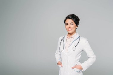 gri izole ceplerinde elleri ile kamera poz stetoskop ile neşeli karışık yarış doktoru