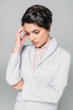 yorgun karışık ırk doktor gri izole baş yakınında el tutarken aşağı bakıyor