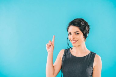 cheerful mixed race call center operator in headset showing idea sign isolated on blue clipart
