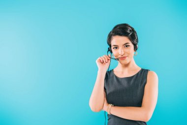 beautiful mixed race call center operator in headset looking at camera isolated on blue clipart