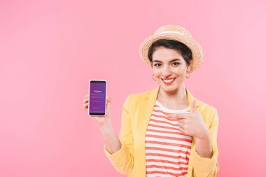 Kiev, Ukrayna - 24 Nisan 2019: Pembe ekranda Instagram uygulaması ile akıllı telefon gösteren gülümseyen karışık yarış kadın.