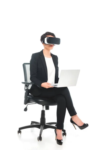 オフィスの椅子に座りながらノートパソコンを使って仮想現実のヘッドセットを身に着けている若い男女が — ストック写真