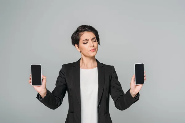 Skeptic Mixed Race Businesswoman Holding Smartphones Blank Screen Isolated Grey — Stock Photo, Image