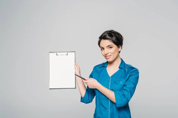 Pretty Mixed Race Doctor Pointing Blank Paper Clipboard Isolated Grey — Stock Photo, Image