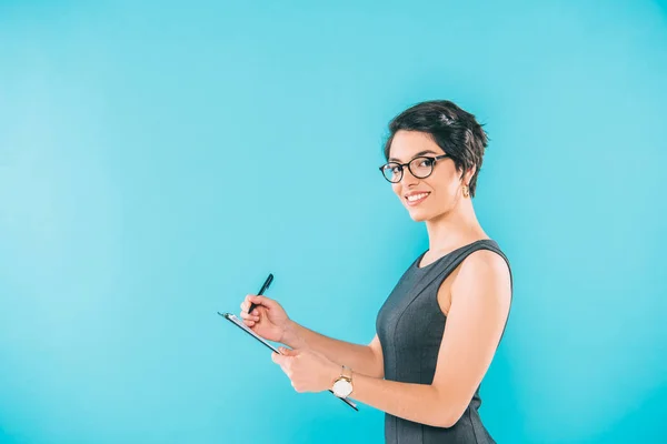 Atractiva Mujer Negocios Raza Mixta Escribiendo Portapapeles Mientras Mira Cámara —  Fotos de Stock