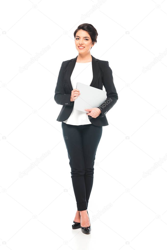 attractive mixed race businesswoman holding laptop and looking at camera on white background