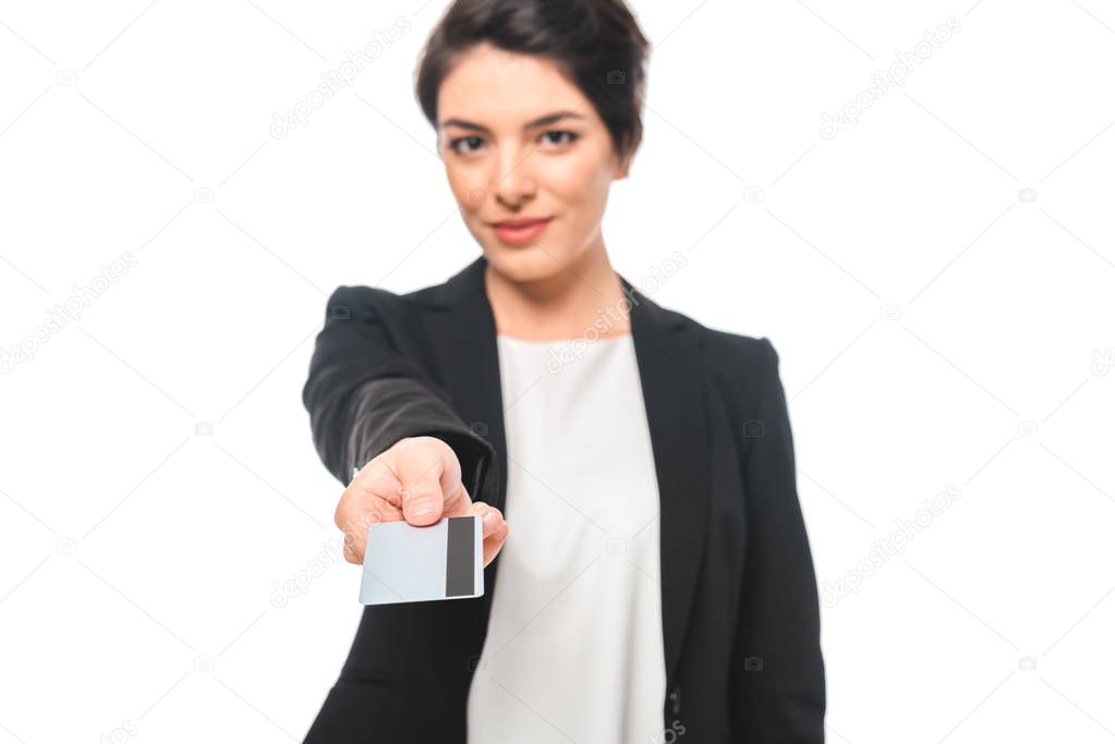 selective focus of attractive mixed race businesswoman presenting credit card while smiling at camera isolated on white
