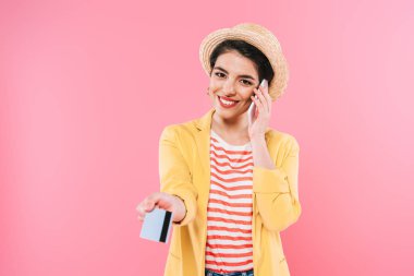 neşeli karışık ırk kadın akıllı telefon konuşuyor ve pembe izole kredi kartı tutarak