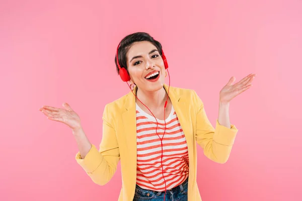 Vrolijke Mixed Race Vrouw Luisteren Muziek Koptelefoon Gebaren Geïsoleerd Roze — Stockfoto