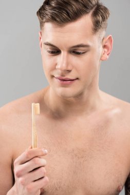 gri izole ahşap diş fırçası ile diş fırçalama çıplak genç adam