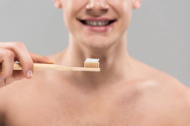 gri izole ahşap diş fırçası ile diş fırçalama çıplak genç adam kırpılmış görünümü