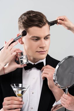 gri izole kokteyl cam tutarak resmi giyim adam için makyaj yapan makyaj sanatçıları kırpılmış görünümü