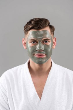 gri izole beyaz bornoz kil maskesi ile gülümseyen genç adamın ön görünümü