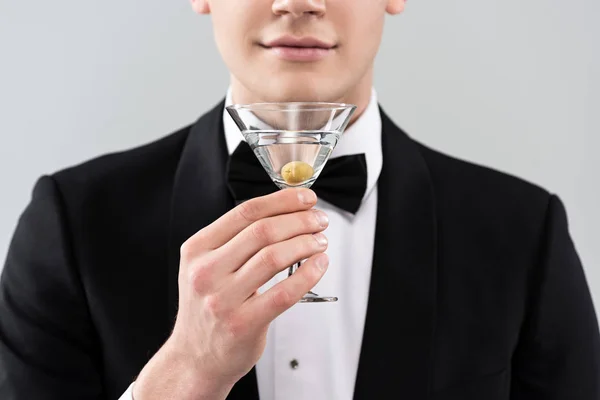 グレーに隔離されたカクテルのグラスを保持するフォーマルな服を着た笑顔の男のトリミングされたビュー — ストック写真