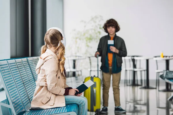 待合場でパスポートと黄色のスーツケースを持って立っている少年を見て 十代の子供の選択的な焦点 — ストック写真