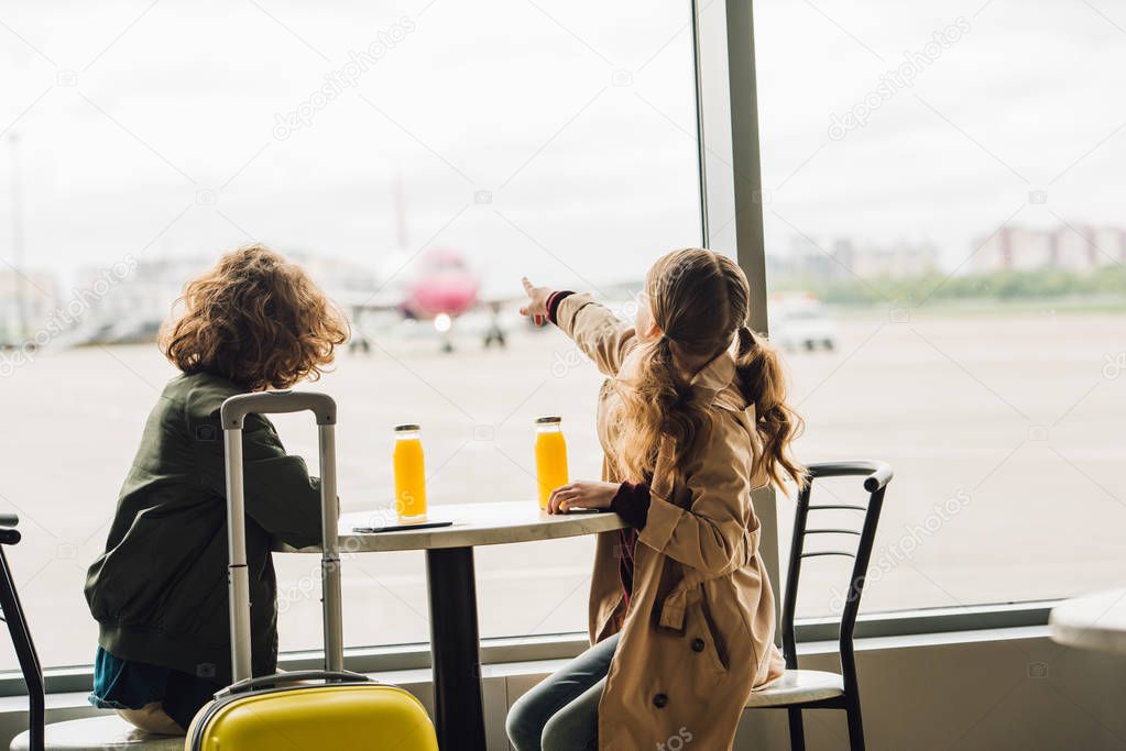 preteen kid pointing with finger at plane and boy looking on it