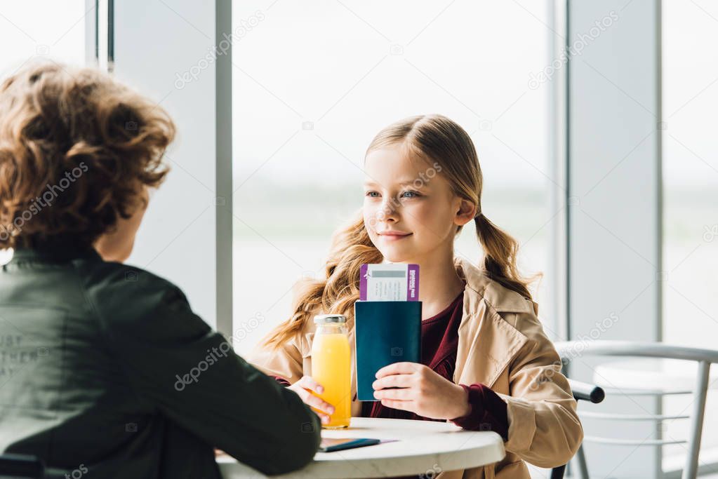 preteen kid showing passport and air ticket to boy in waiting hall