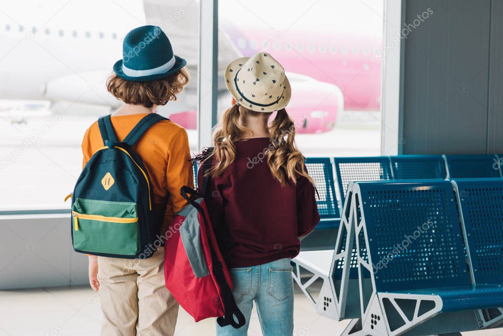 back view of preteen kids with backpacks in waiting hall