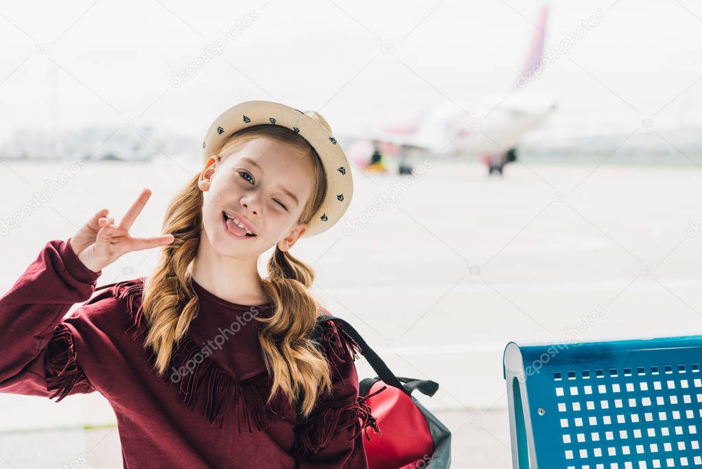 cute preteen kid sticking out tongue and showing Peace Sign in airport